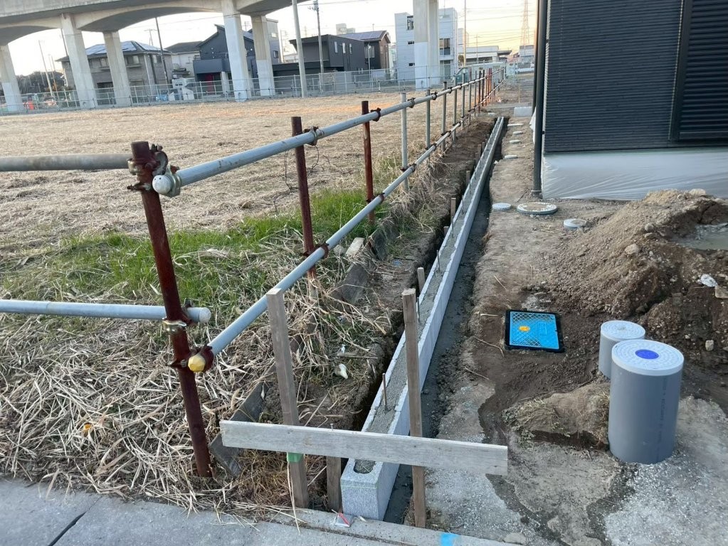 埼玉県八潮市O様邸の境界ブロック据え付け施工中。通りと天端レベルを確認しながらブロックを設置している様子